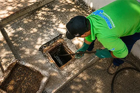 Técnico utilizando o hidrojateamento de alta pressão para desentupimento de tubulações externas.