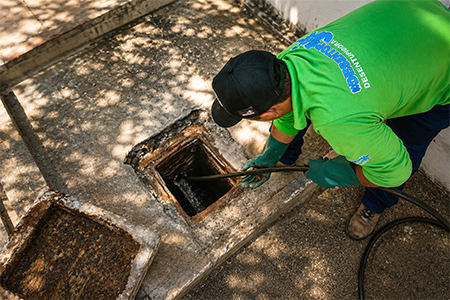 Técnico utilizando o hidrojateamento de alta pressão para desentupimento de tubulações externas.